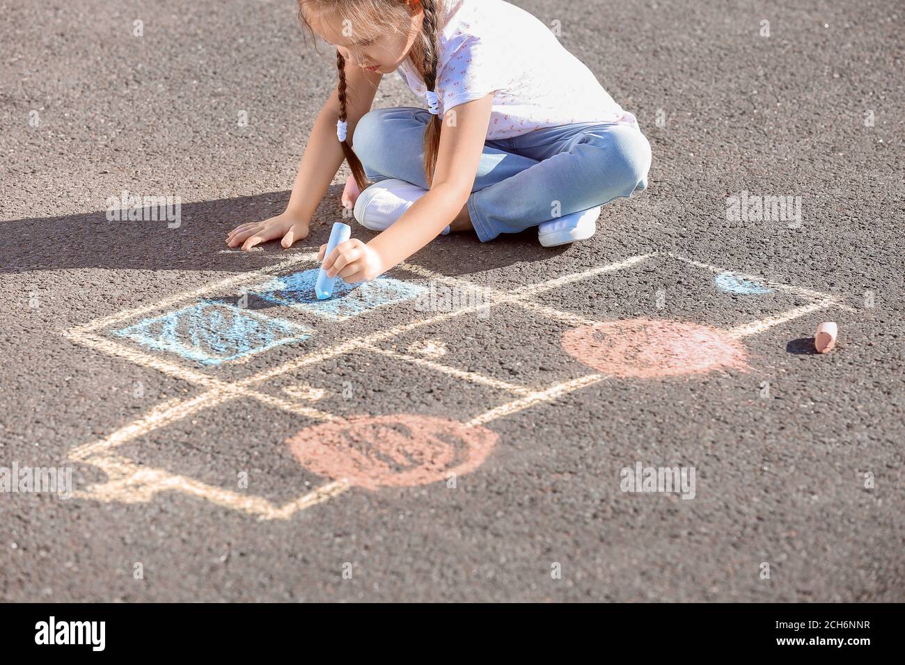 Little girl drawing with chalk on asphalt Stock Photo - Alamy