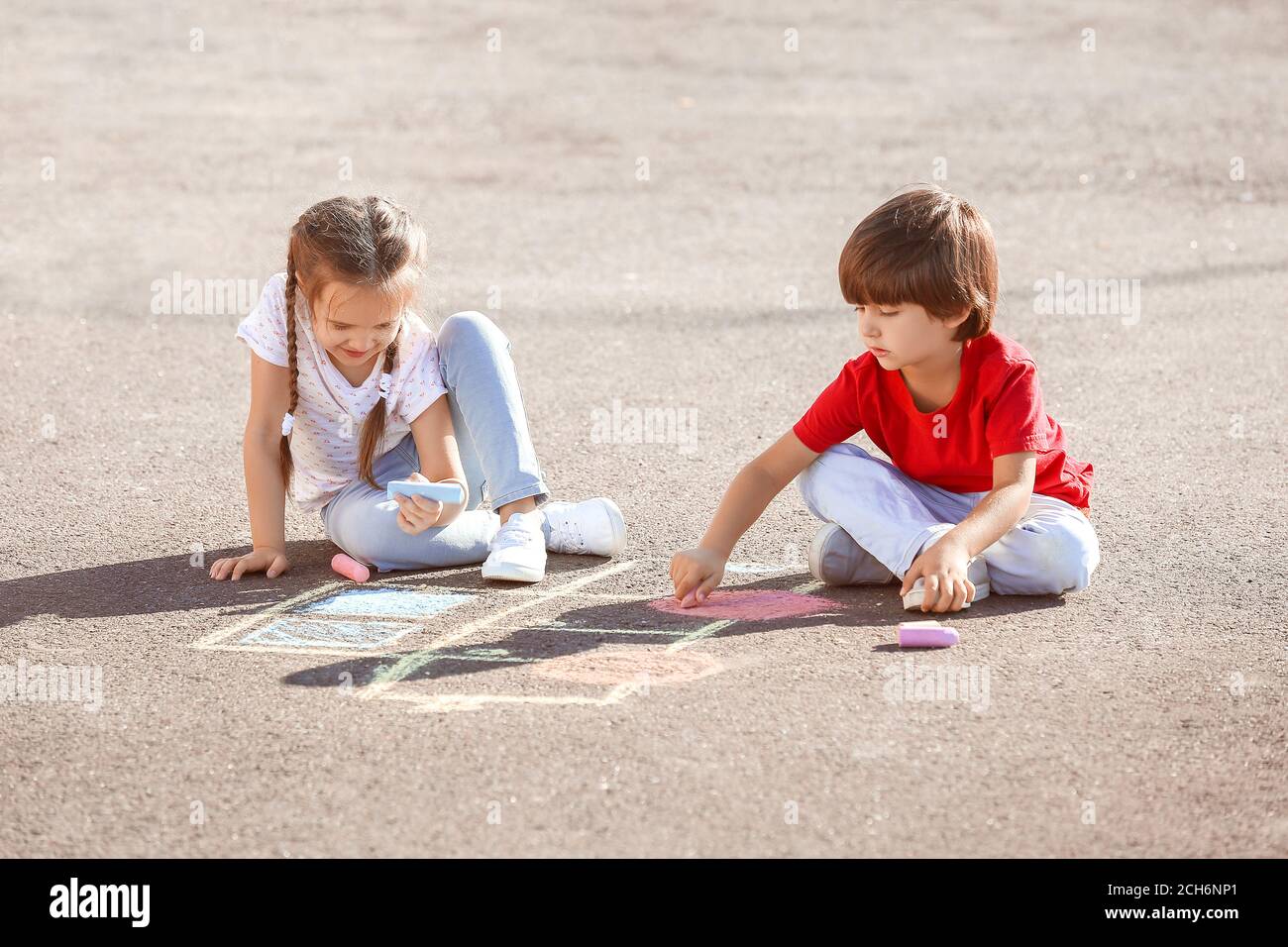 Little children drawing with chalk on asphalt Stock Photo - Alamy