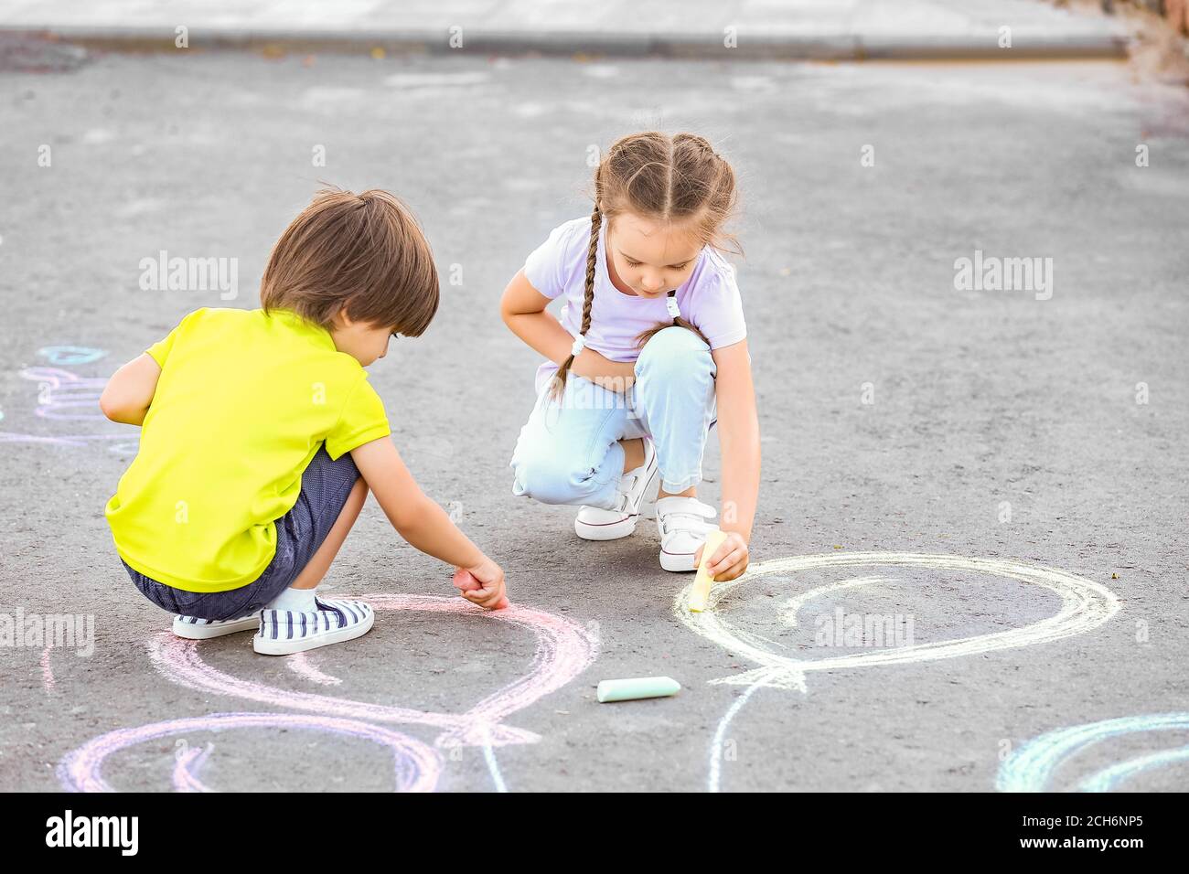 Little children drawing with chalk on asphalt Stock Photo - Alamy