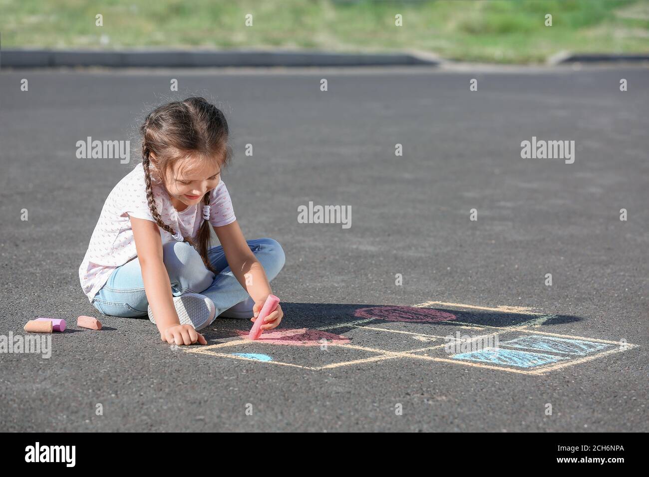 Little girl drawing with chalk on asphalt Stock Photo - Alamy