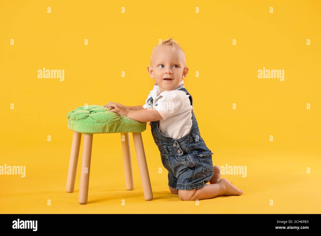 Portrait of cute little baby with stool on color background Stock Photo