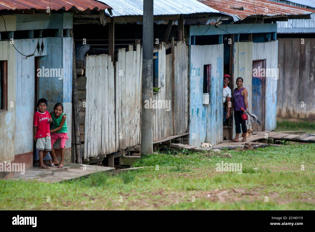 People stand at the entrance to their wooden houses in the Amazon River