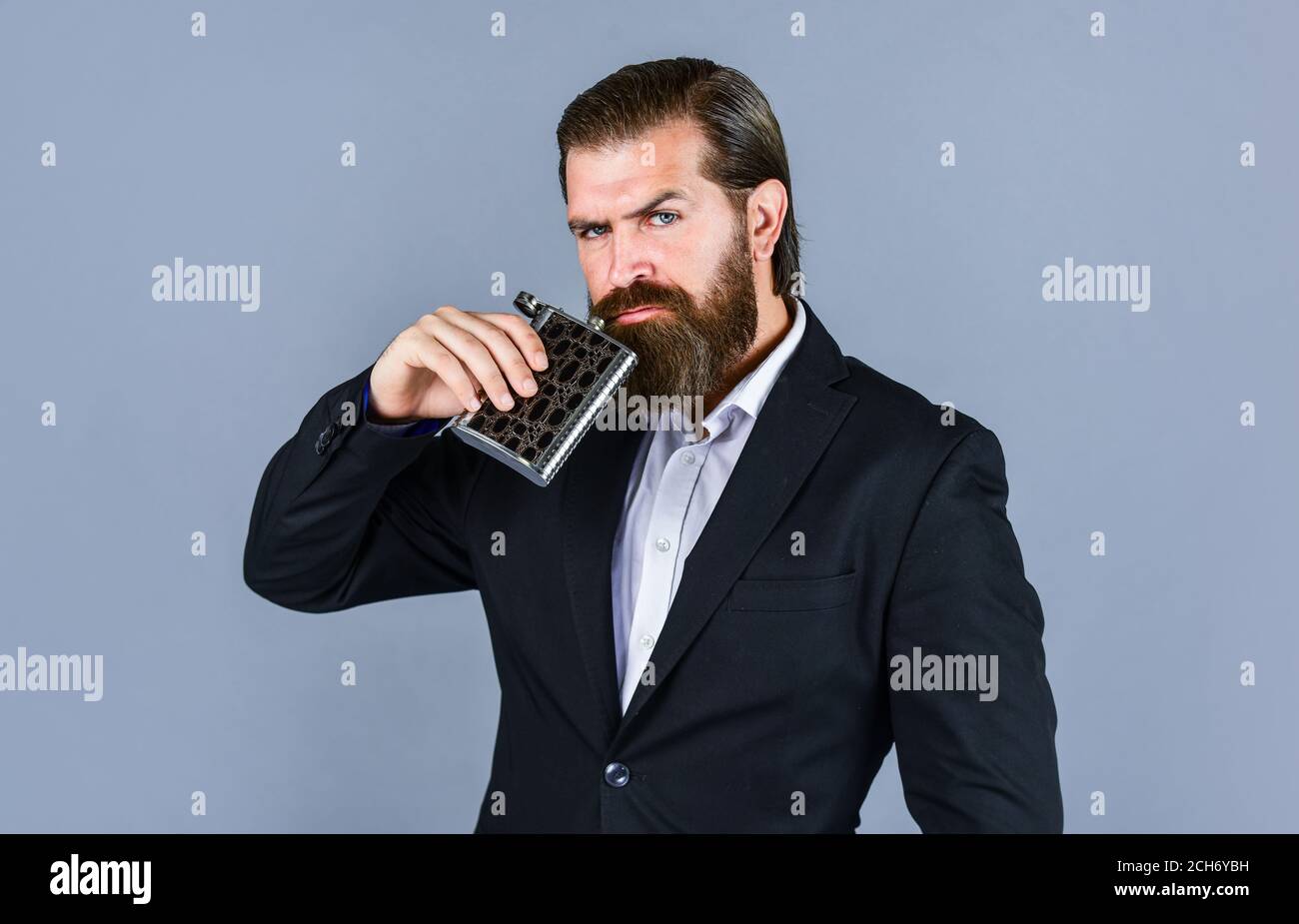 bearded hipster in suit hold metal flask for alcohol. Alcohol drink concept. Have alcohol drink with you. Always with me. Flat metal bottle for alcohol. man with elegant look. Stock Photo