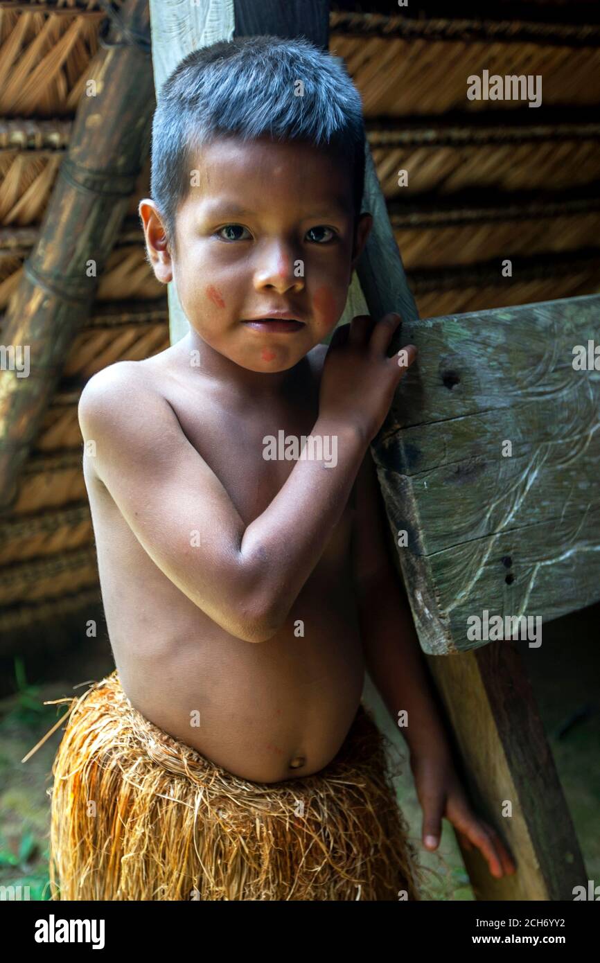 A Peruvian boy dressed in tradition Indian grass skirt at a village near Iquitos on the Amazon River in Peru. Stock Photo