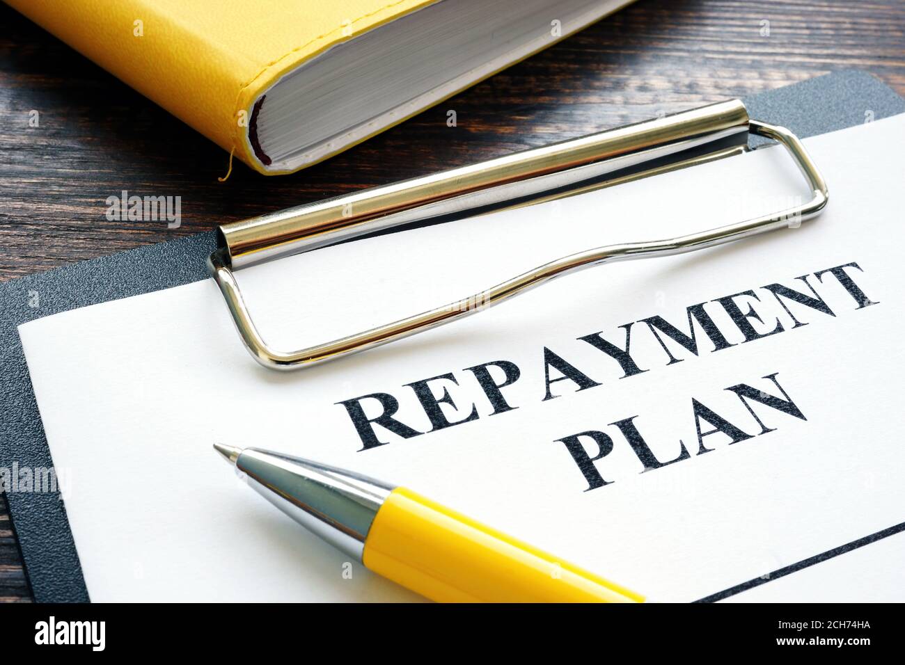 Repayment plan with clipboard and yellow pen. Stock Photo
