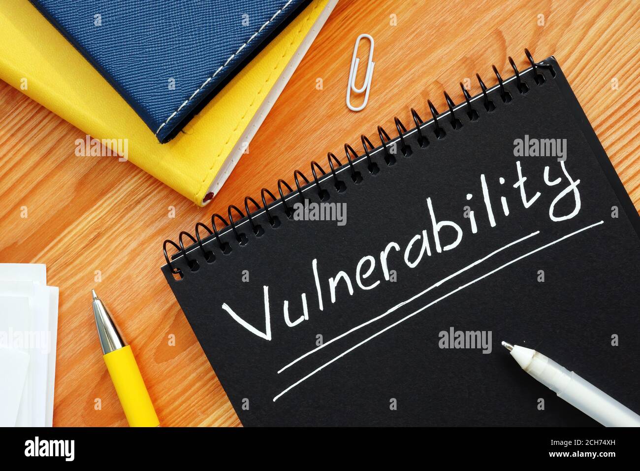 Vulnerability is written in white pencil on a black page. Stock Photo