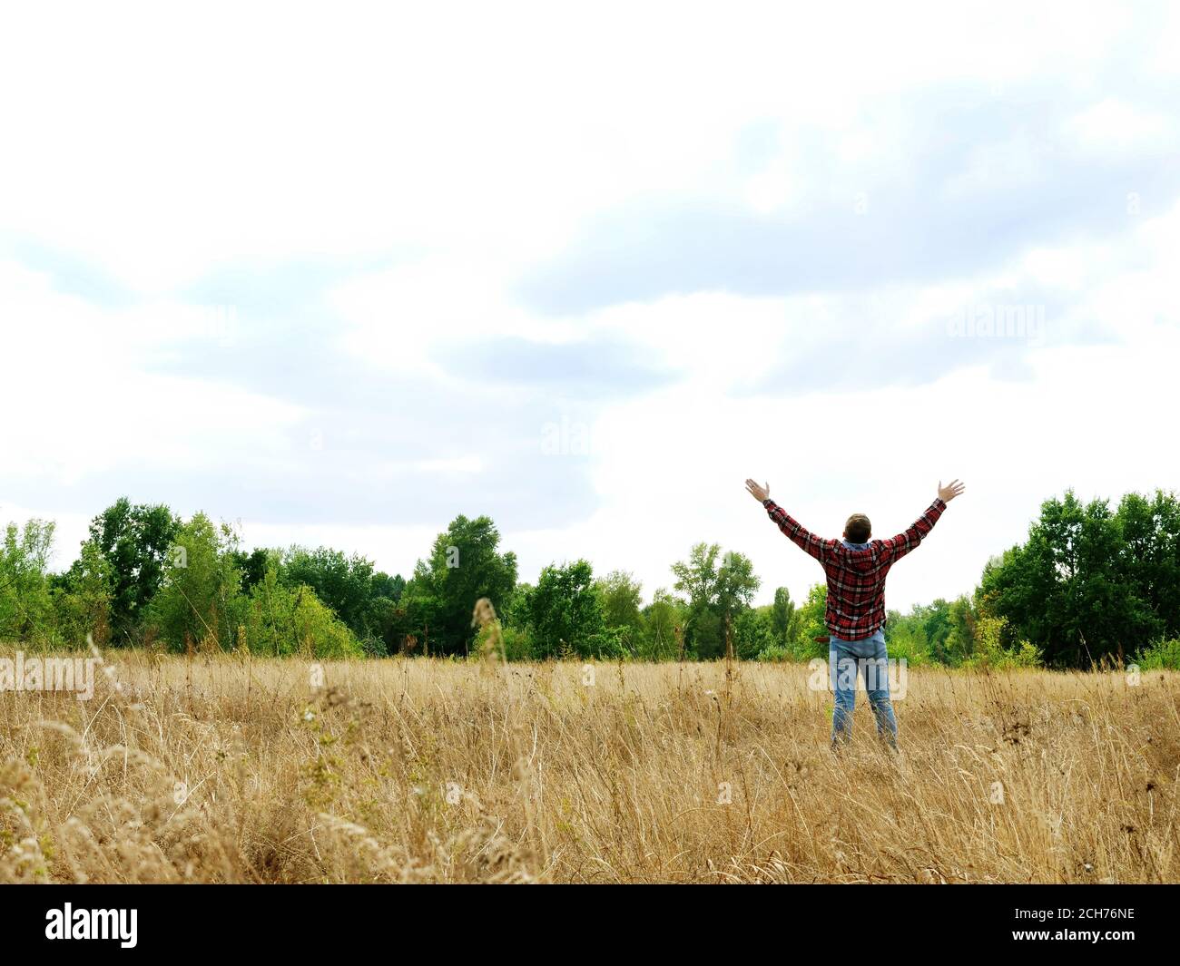 A man in an autumn field stretches out his hands to the sky. Stock Photo