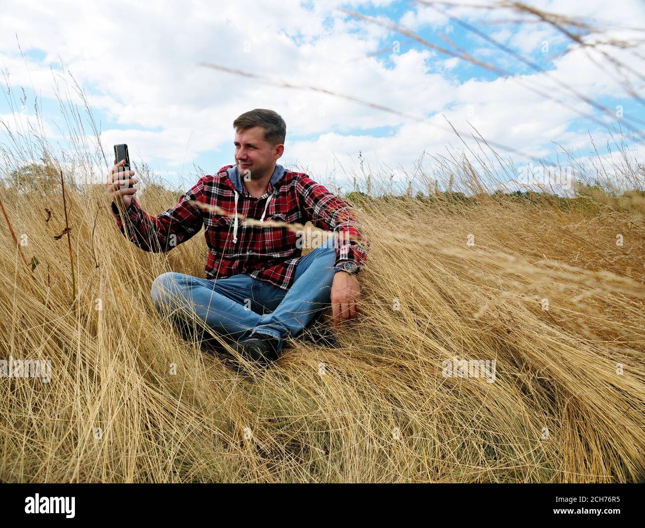 A man in the autumn nature takes a selfie and uses a smartphone. Stock Photo