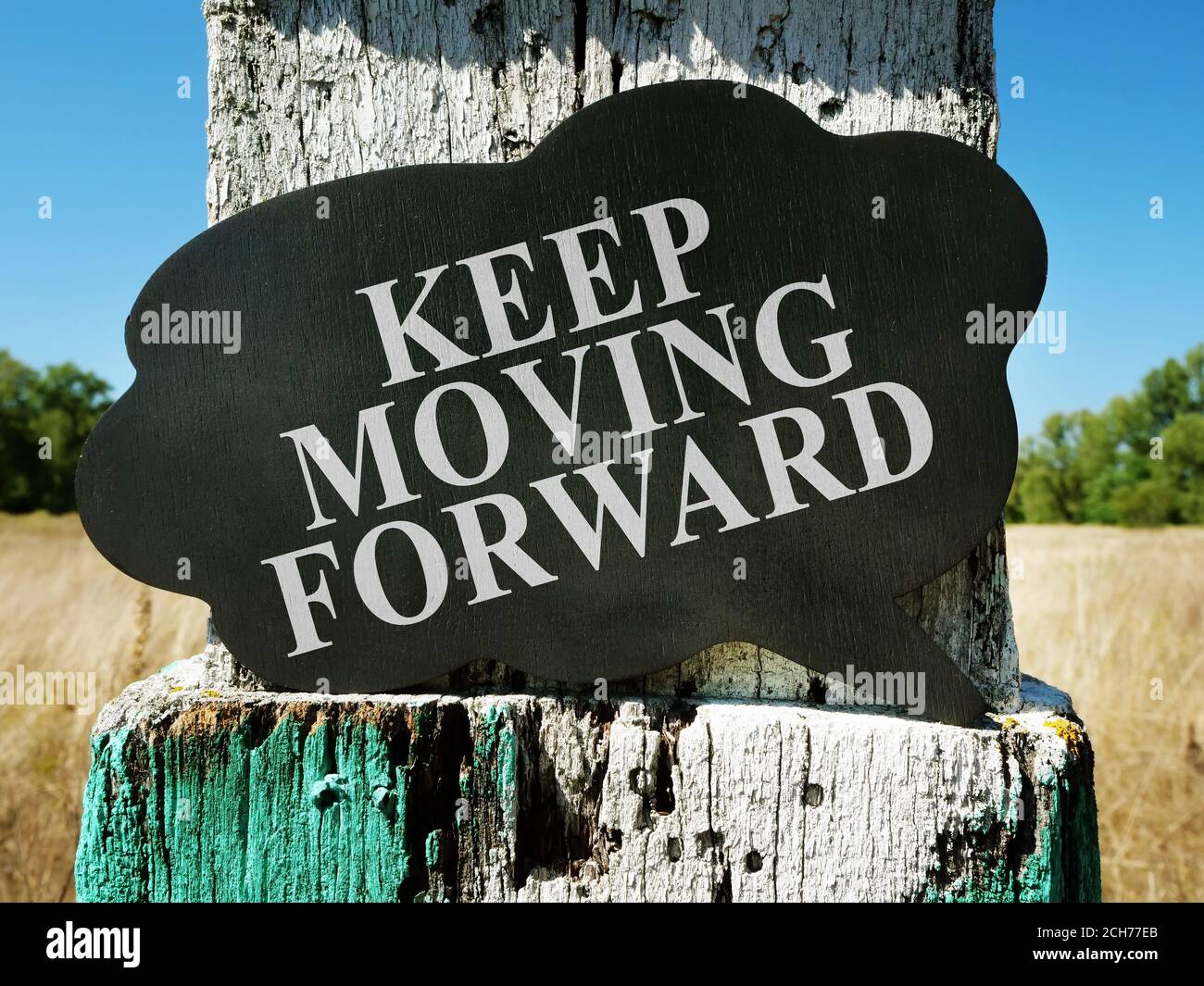 Keep moving forward motivational quote. Old milestone on the field. Stock Photo