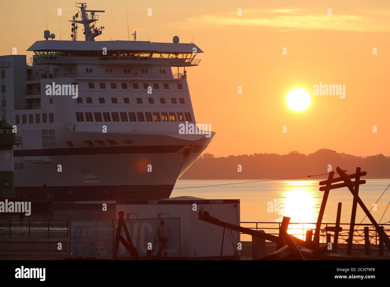 14 September 2020, Schleswig-Holstein, Travemünde: The sun rises atmospherically at the mouth of the Baltic Sea in Travemünde, while the ferry Nils Holgersson enters the harbour. A high pressure area provides hot late summer weather in Germany. Photo: Bodo Marks/dpa Stock Photo