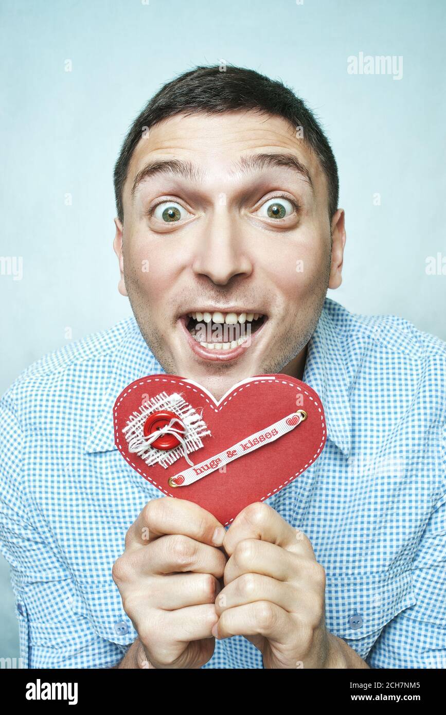 Crazy happy guy holding red valentine card with hugs and kisses ribbon Stock Photo