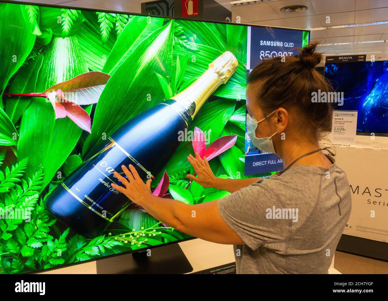 Woman wearing face mask looking at Samsung High definition QLED 8K Q850T television, TV screen in store. Stock Photo