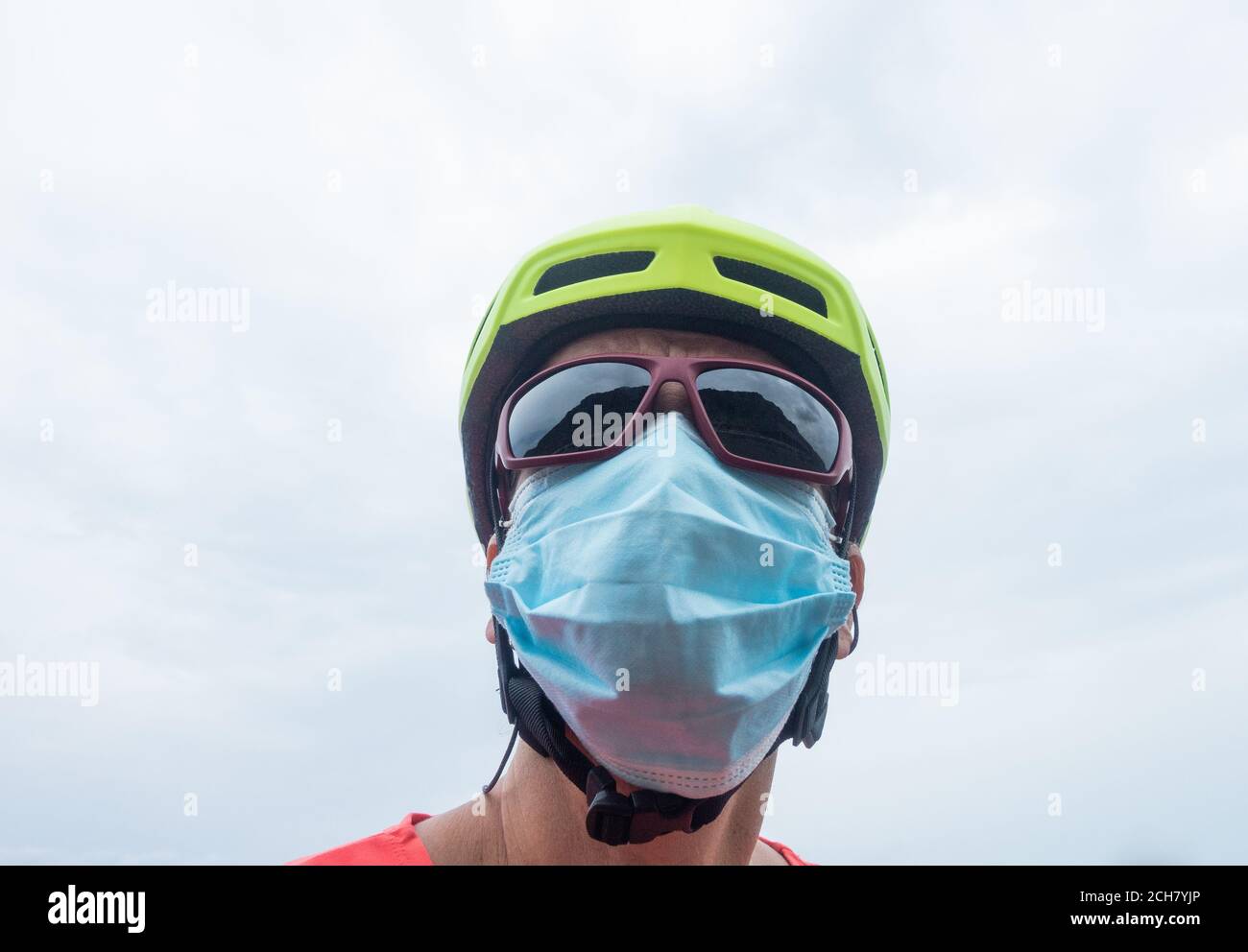 Mature female cyclist wearing cycling helmet, sunglasses and face mask, covering. Stock Photo