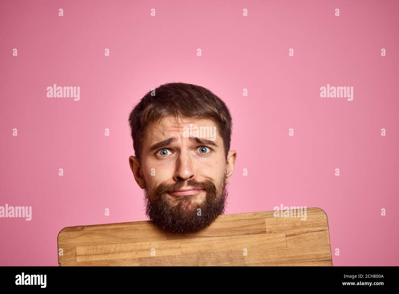 guy holding kitchen board and spatula in hand on pink background