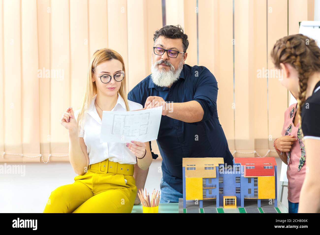 Multiethnic architects working on blueprint construction mockup with team Stock Photo