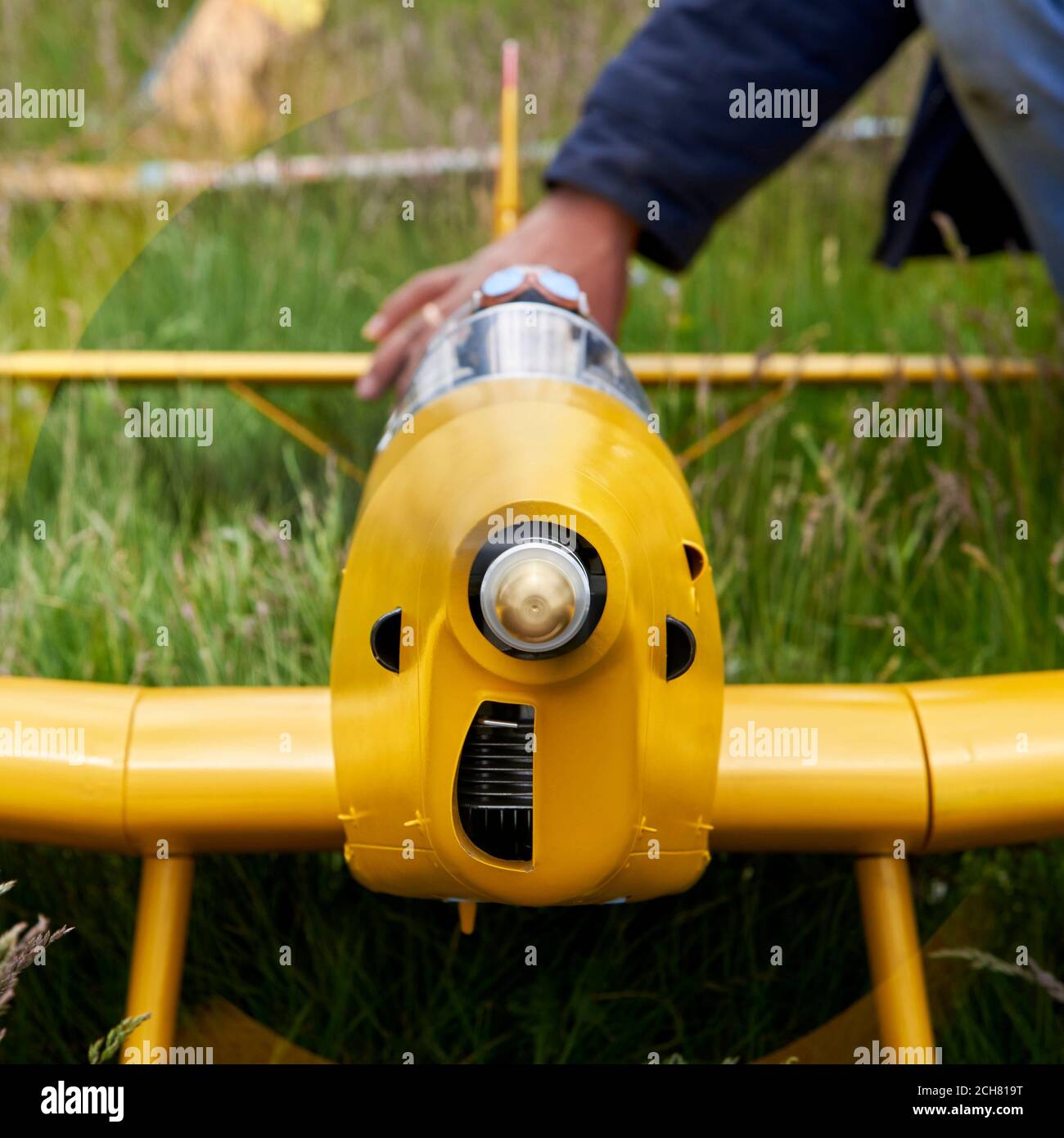 A man prepares a radiocontrolled aircraft for flight on the field in