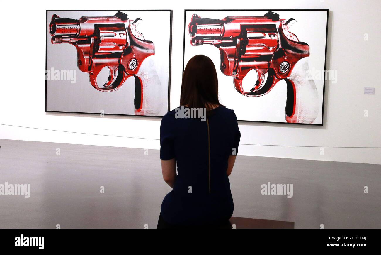 A woman looks at GUN 1981 Acrylic and silkscreen on two canvases, part of the Andy Warhol exhibition at the Tate Gallery, Liverpool. Stock Photo