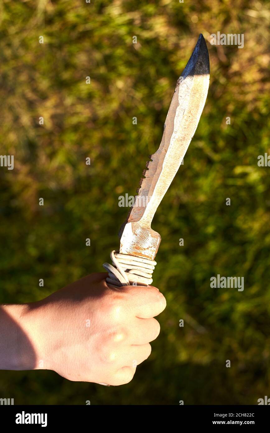 Sharp old notch knife in woman's hand on grass background Stock Photo
