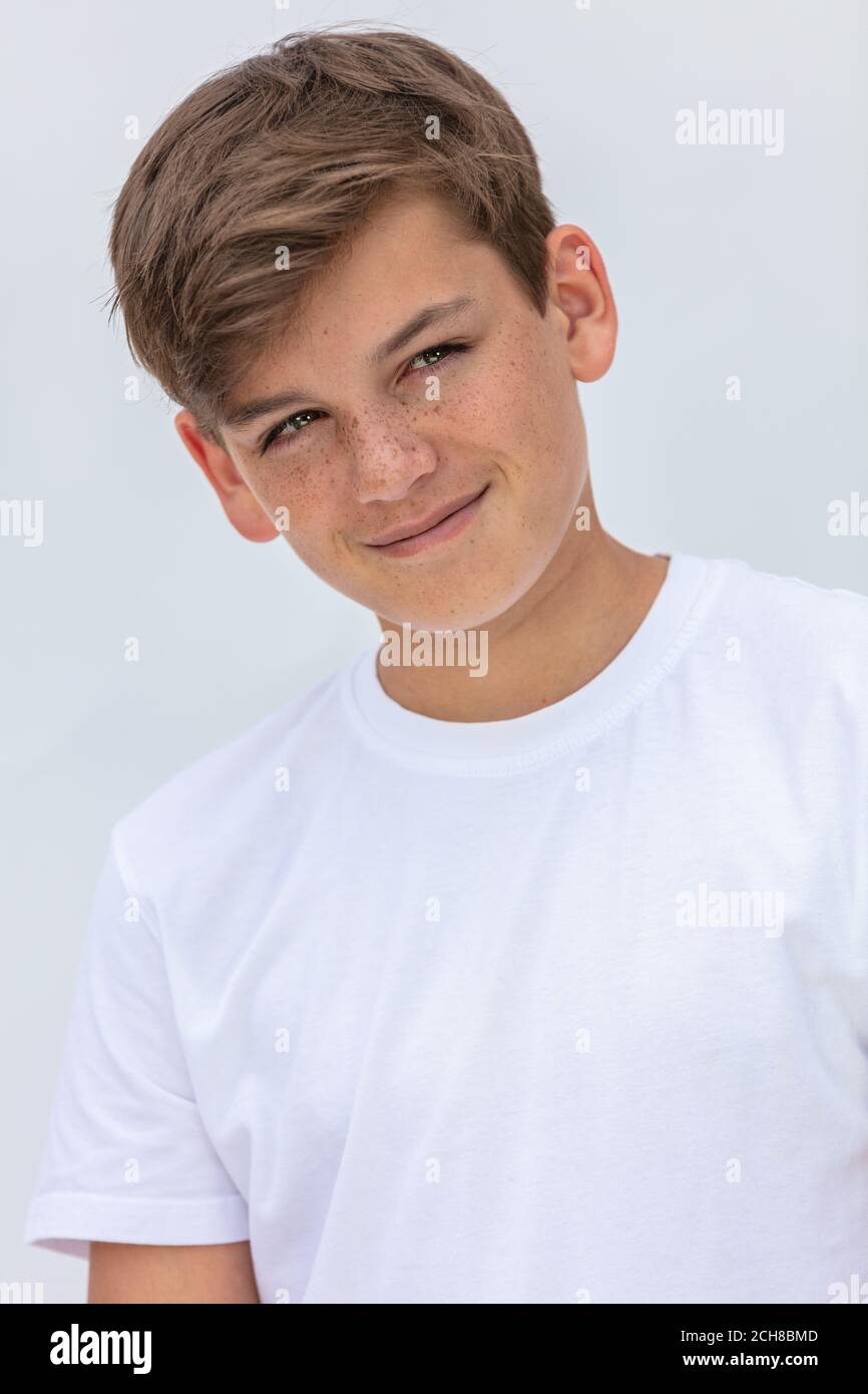 White background studio portrait of a smiling happy boy teenager teen male child wearing a white t-shirt Stock Photo
