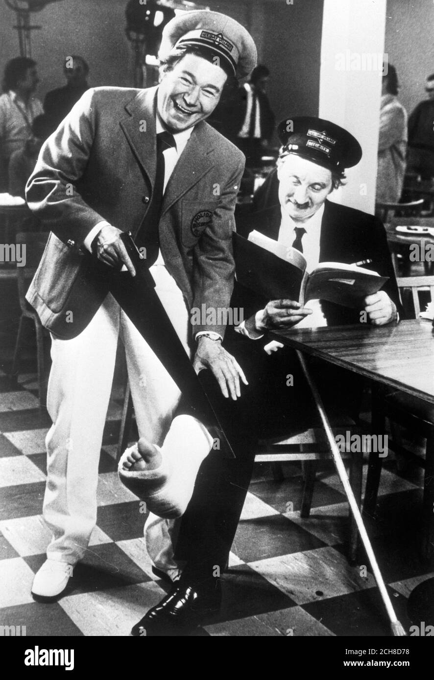 Actor Stephen Lewis (right), aka bus inspector Blake from On the Buses, larks around with Reg Varney on the set of Holiday on the Buses. Lewis cracked a bone in his ankle and the screenplay was rewritten so he could play a 'limping' role. Stock Photo