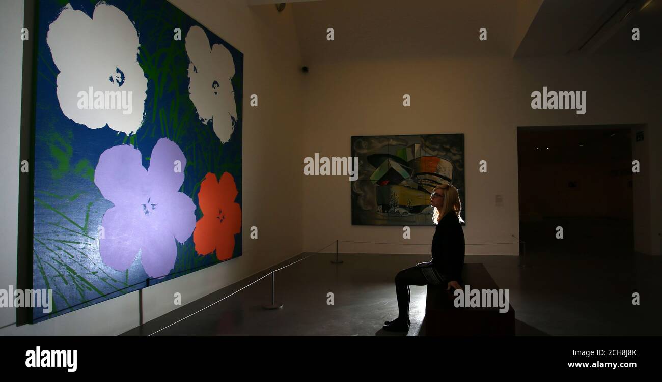 A member of the public looks at a painting called Warhol Flowers by Elaine Sturtevant which forms part of the Works to Know by Heart: An Imagined Museum exhibition at Tate Liverpool. Stock Photo