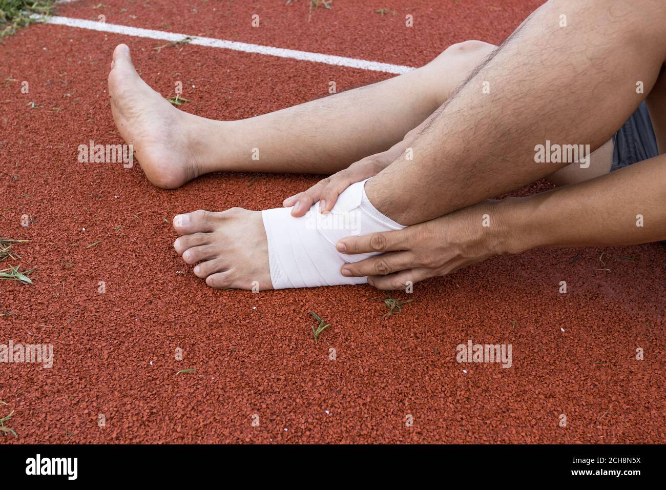 man applying compression bandage onto ankle injury of a football player