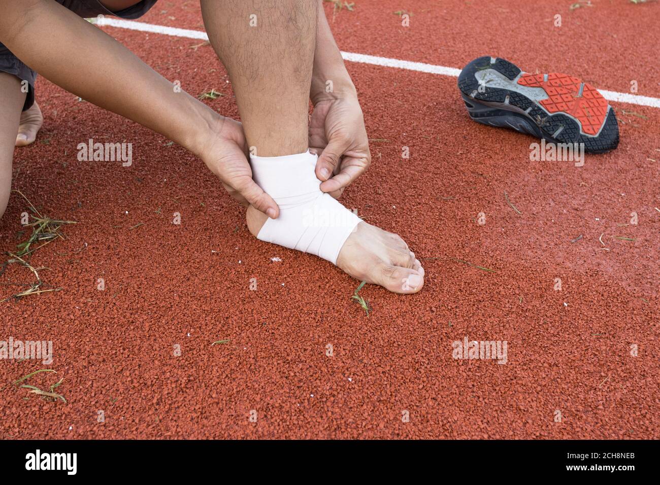 man applying compression bandage onto ankle injury of a football player