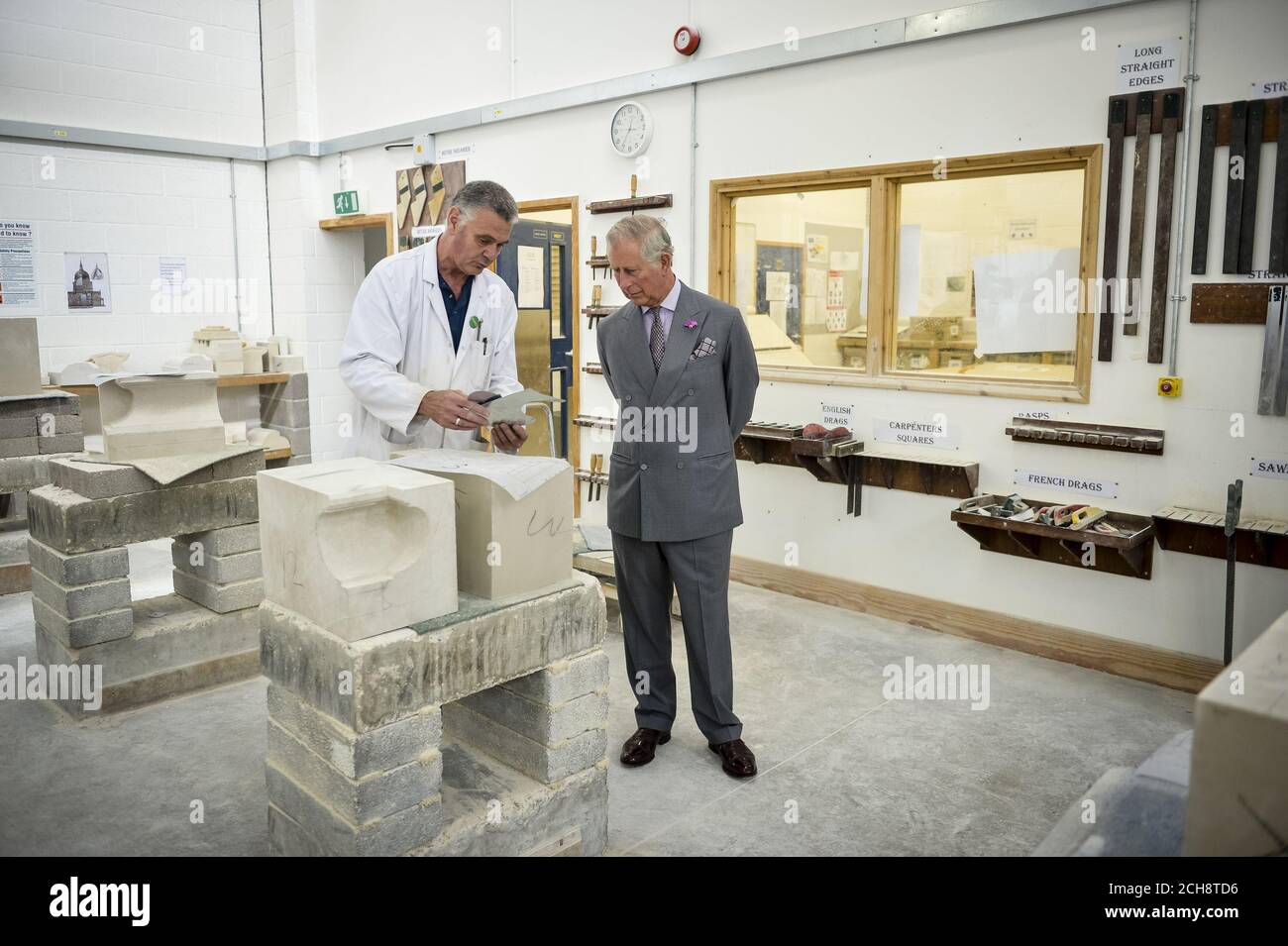The Prince of Wales is shown examples of stonemasonary by tutor Richard Mortime at the Dorset Centre for Creative Arts, during a visit to Poundbury, Dorset. Stock Photo