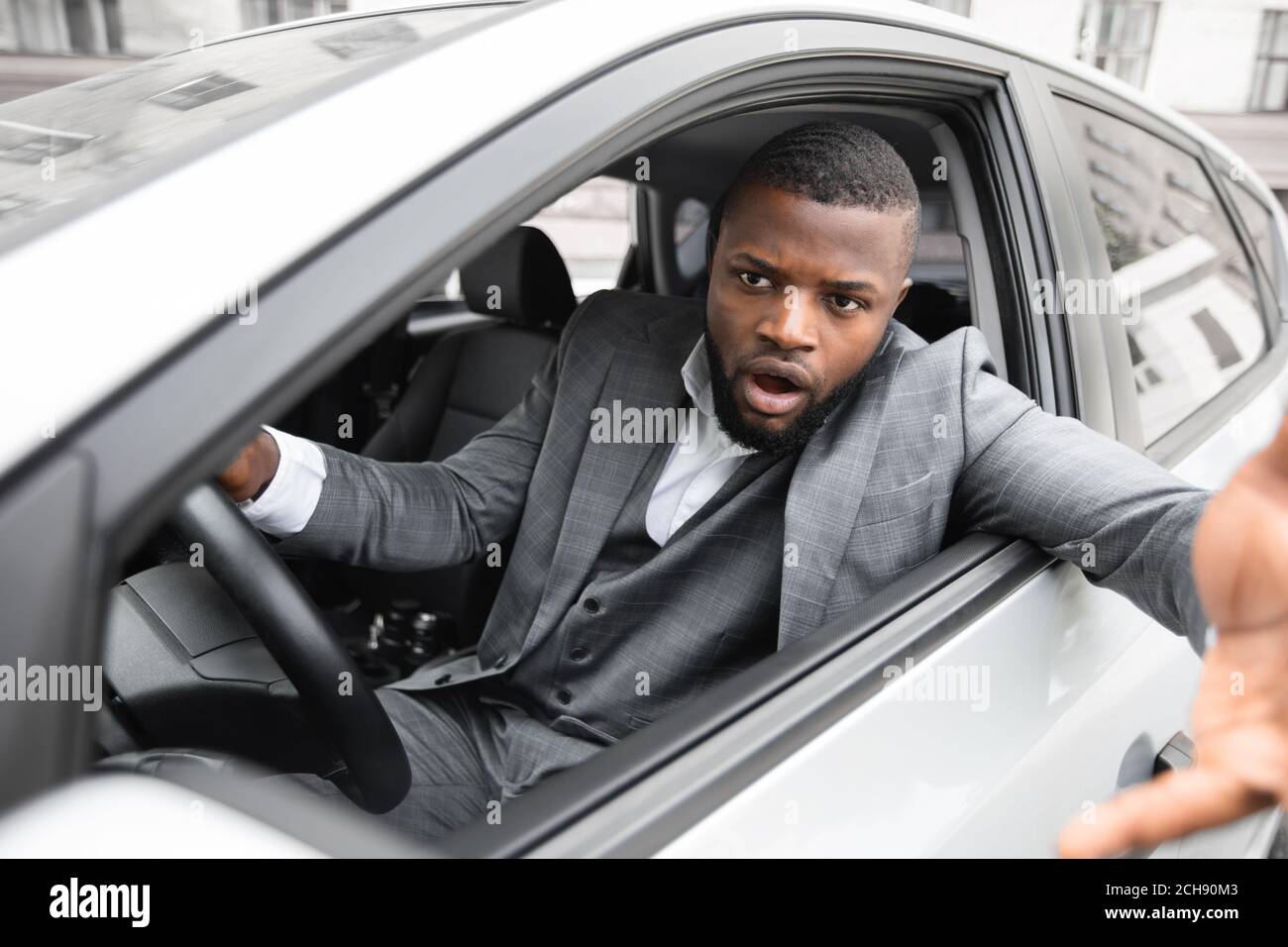 Angry black man driver gesturing and shouting while driving car Stock Photo