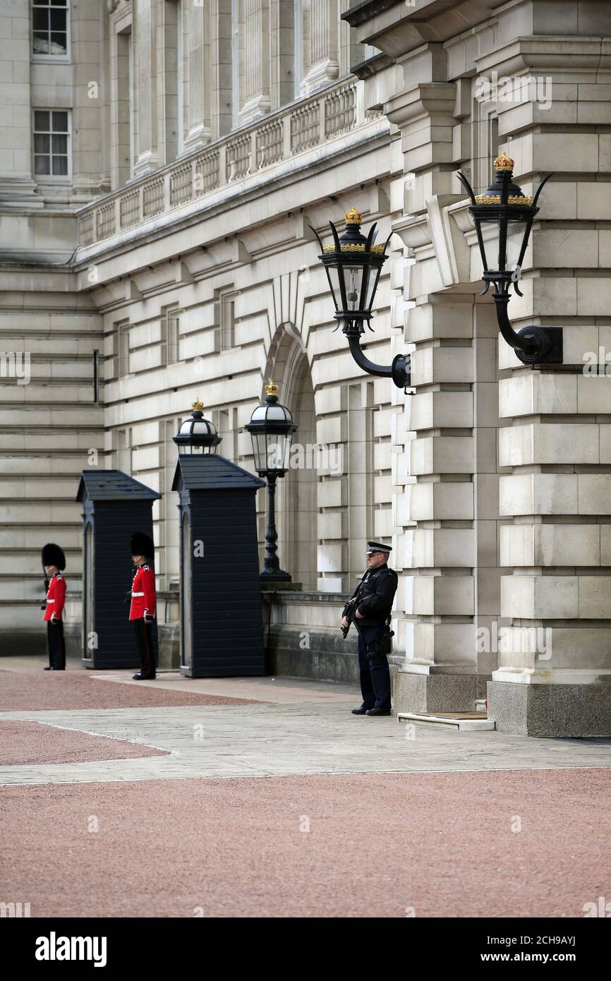 An armed police officer and soldiers from the Irish Guards in the forecourt of Buckingham Palace in central London. Scotland Yard has said that a 41-year-old man was arrested after scaling a perimeter wall at the palace Wednesday night. Stock Photo