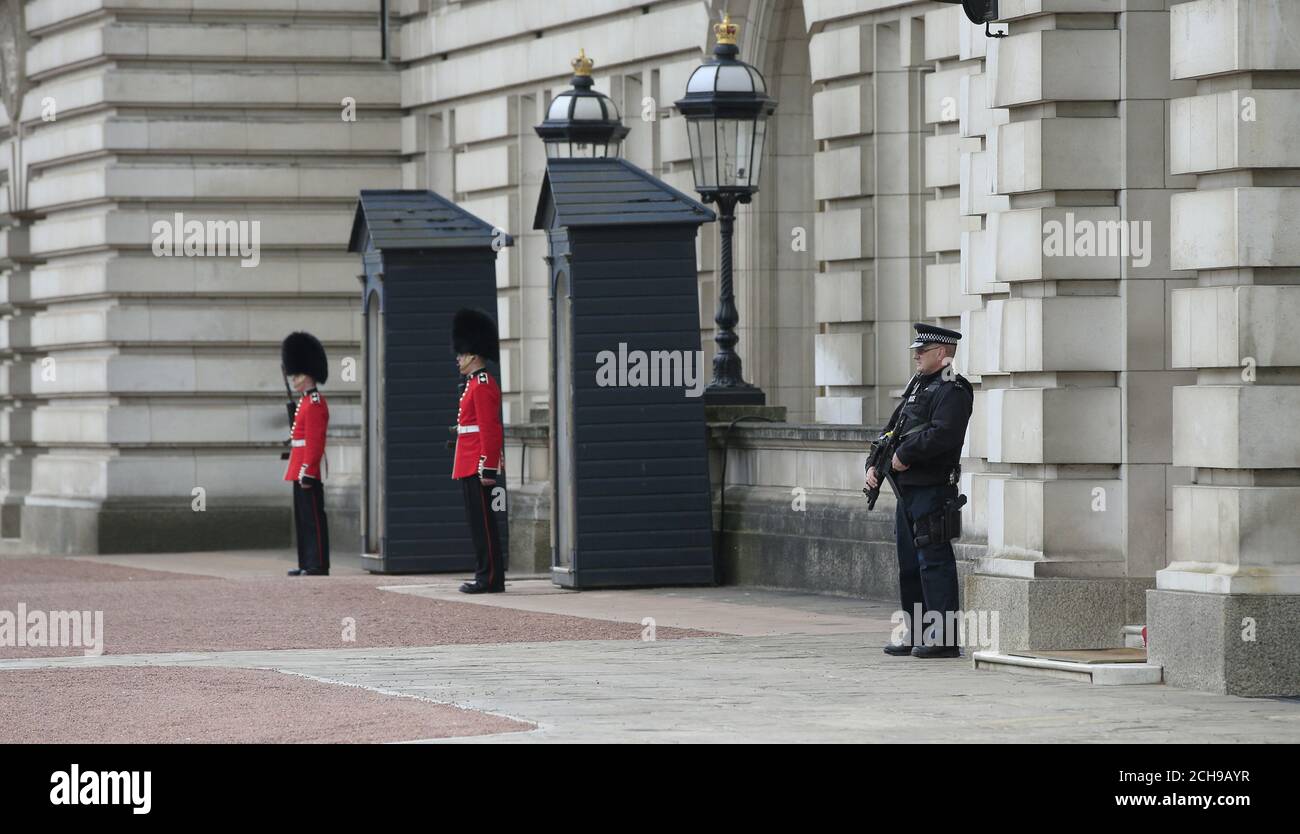 An armed police officer and soldiers from the Irish Guards in the forecourt of Buckingham Palace in central London. Scotland Yard has said that a 41-year-old man was arrested after scaling a perimeter wall at the palace Wednesday night. Stock Photo