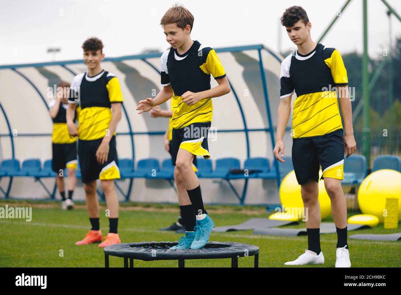 Soccer training trampoline. Group of young boys in sports football club practicing on jumping trampoline. Youth athletes improving stability skills Stock Photo
