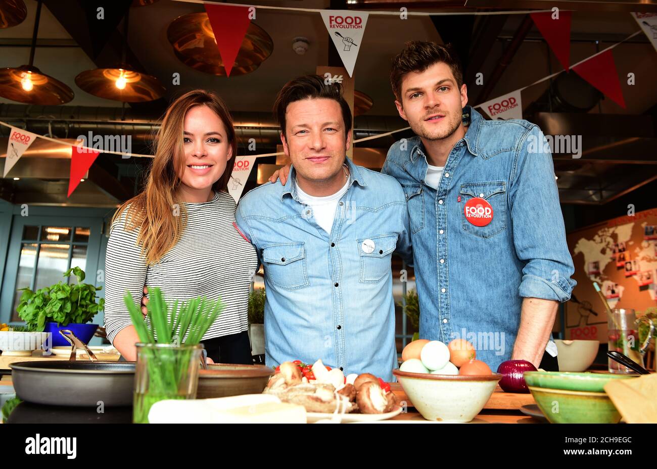 Jamie Oliver with Tanya Burr (left) and Jim Chapman (right) at his Cookery School in Westfield Shopping Centre in London, as they launch a Facebook 'live' event that will feature chefs from ten countries encouraging viewers to cook healthy dishes from scratch, on Food Revolution Day which is a part of the Food Revolution campaign aimed at tackling the issues of child malnutrition and obesity. Stock Photo