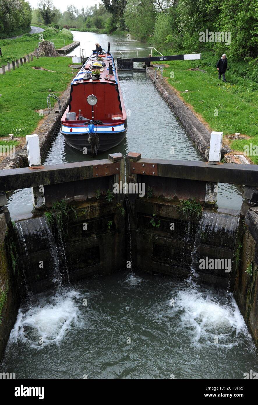 A canal boat is navigated through a lock on the Kennet and Avon canal near to Froxfield in Wiltshire. Stock Photo