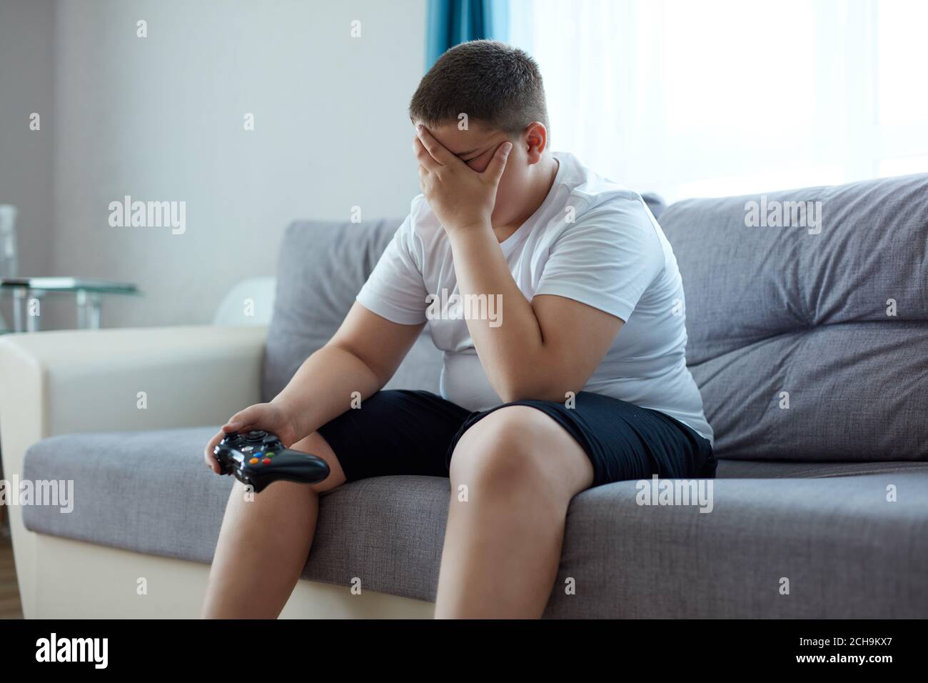 sad fat boy is upset after losing a video game, sit closing face, alone ...