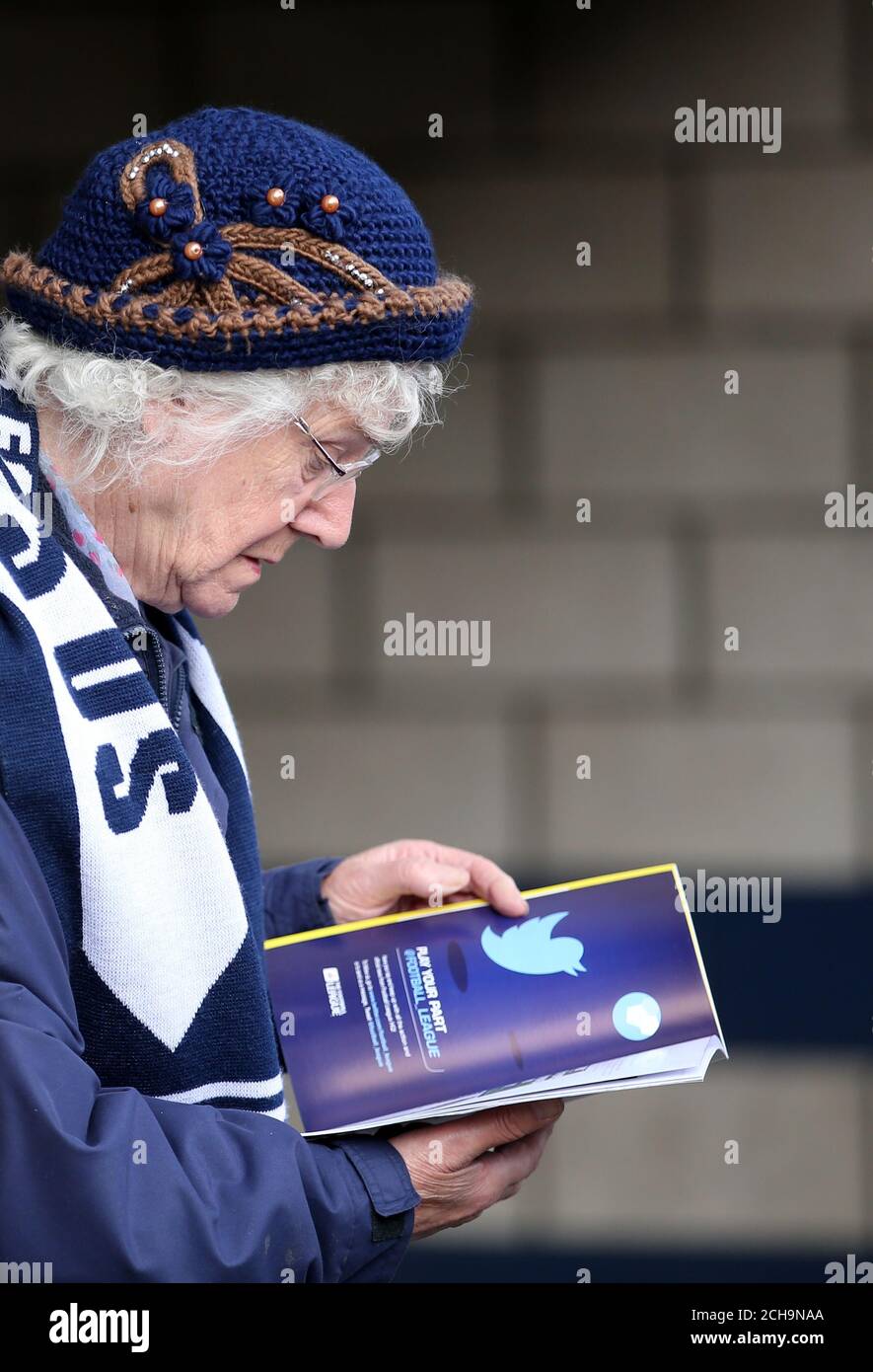 A Millwall fan reads the mach day program prior to kick off Stock Photo