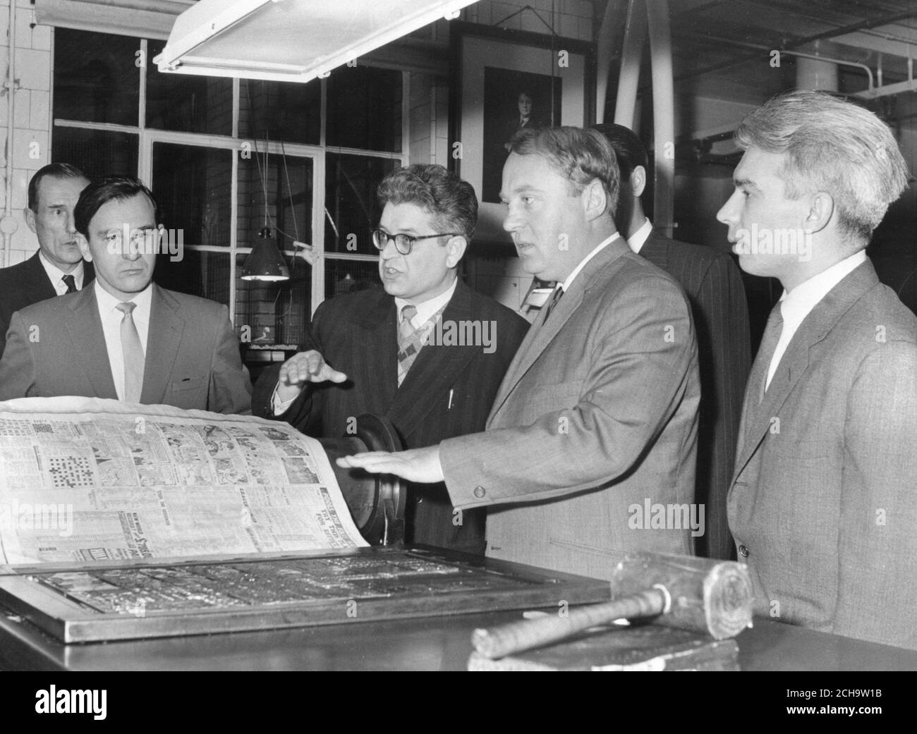 Alexei Adjubei (second right), son-in-law of Nikita Khrushchev and Editor of Izvestia, and Victor Maevsky (glasses), an editor of Pravda, are pictured in the composing room when they paid a surprise visit to the Daily Mail at Northcliffe House, London. On the left is Eugeny Rogov, First Secretary of the Soviet Embassy in London, and right is Vladimir Ossipov, London correspondent of Izvestia. The party, who spent over two hours with the Daily Mail staff, attended the editorial conference and were taken for a tour of Northcliffe House. Stock Photo