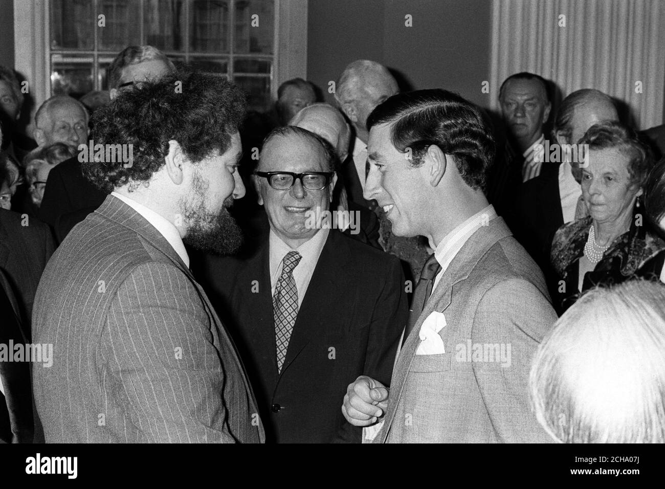 Prince Charles, the Prince of Wales, attends a reception in celebration of the 25th anniversary of the founding of the British Atlantic Committee and the 30th anniversary of the North Atlantic Alliance at the Banqueting Hall, Whitehall, London. (L-R) The Prince of Wales congratulates Robert Hutchinson (l), Defence correspondent of the Press Association who was awarded a prize for two articles on NATO, and Erik de Mauny (centre, with glasses), who made four documentaries entitled 'The Great Divide' on Radio 4. Stock Photo