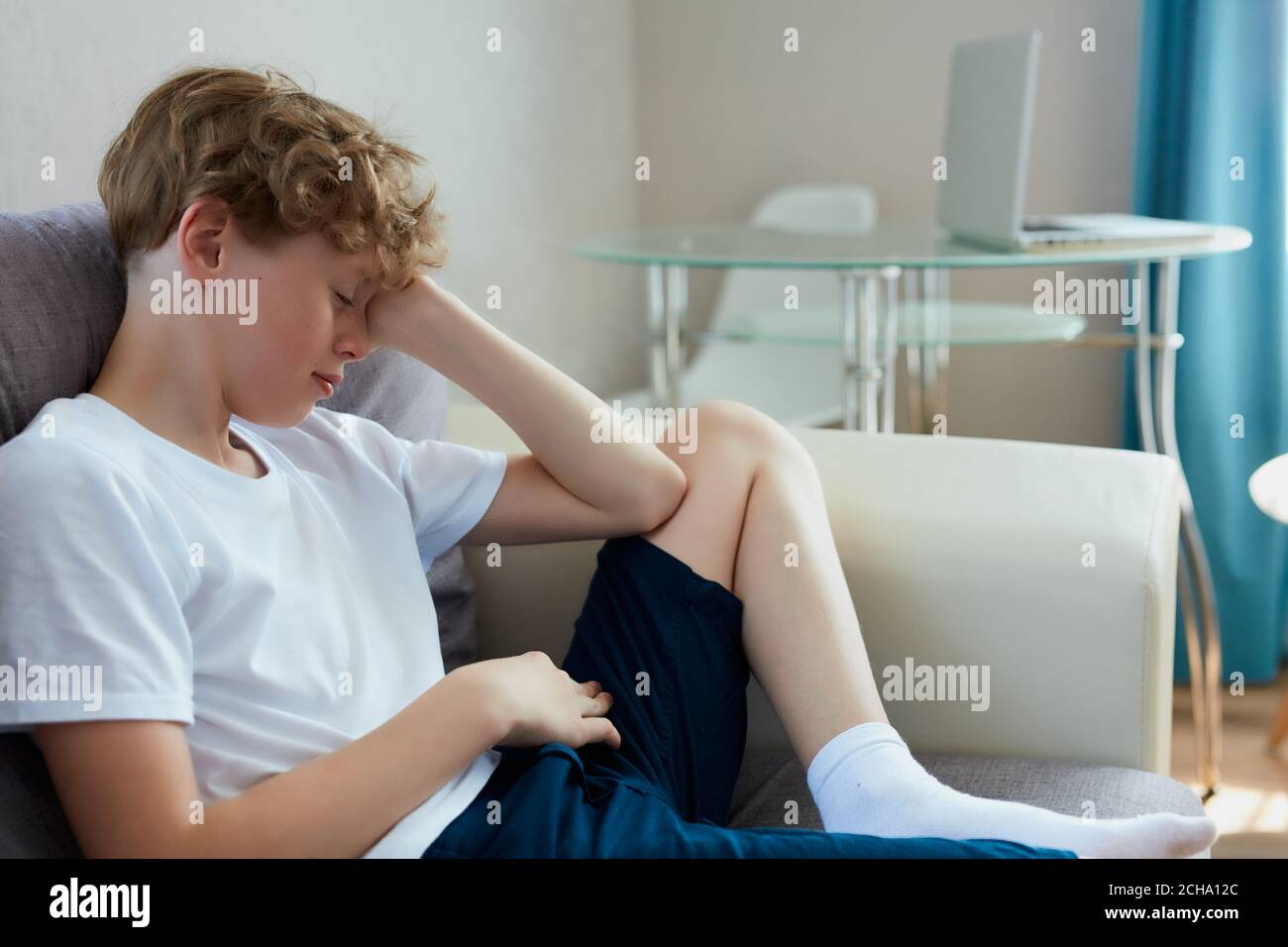 sleepy boy sit on sofa at home. has no enough sleep in the morning, alone Stock Photo