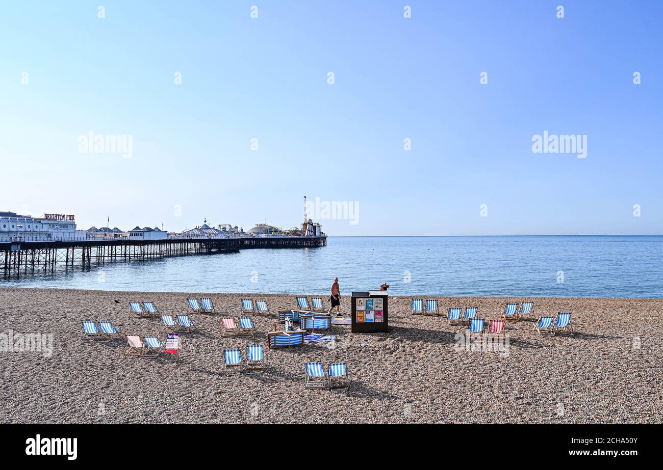 Brighton UK 14th September 2020 - A deckchair attendant lays out chairs on Brighton beach today as temperatures are forecast to reach 30 degrees in parts of the South East  : Credit Simon Dack / Alamy Live News Stock Photo