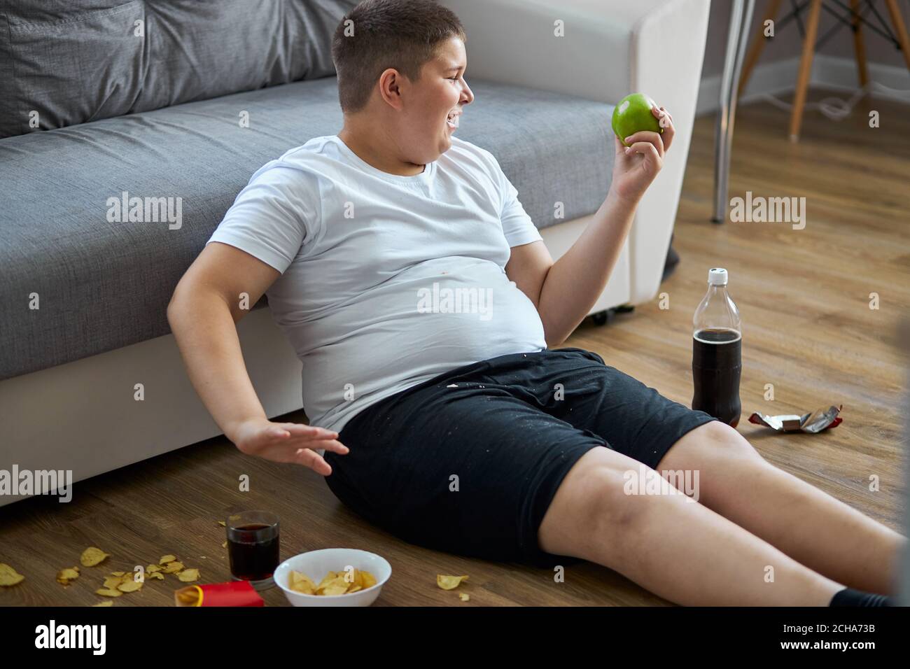 say no to junk food. caucasian fat boy choose apple healthy food instead of junk food. on the floor Stock Photo
