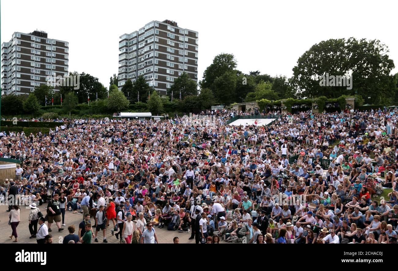 Spectators on Murray Mount watch Andy Murray play Jo-Wilfried Tsonga on the big screen on day nine of the Wimbledon Championships at the All England Lawn tennis and Croquet Club, Wimbledon. Stock Photo