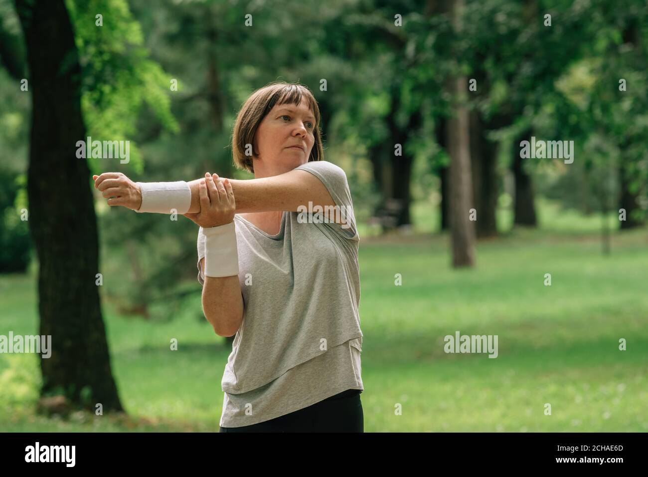 Female jogger stretching muscles and warming up for running exercise in park, selective focus Stock Photo