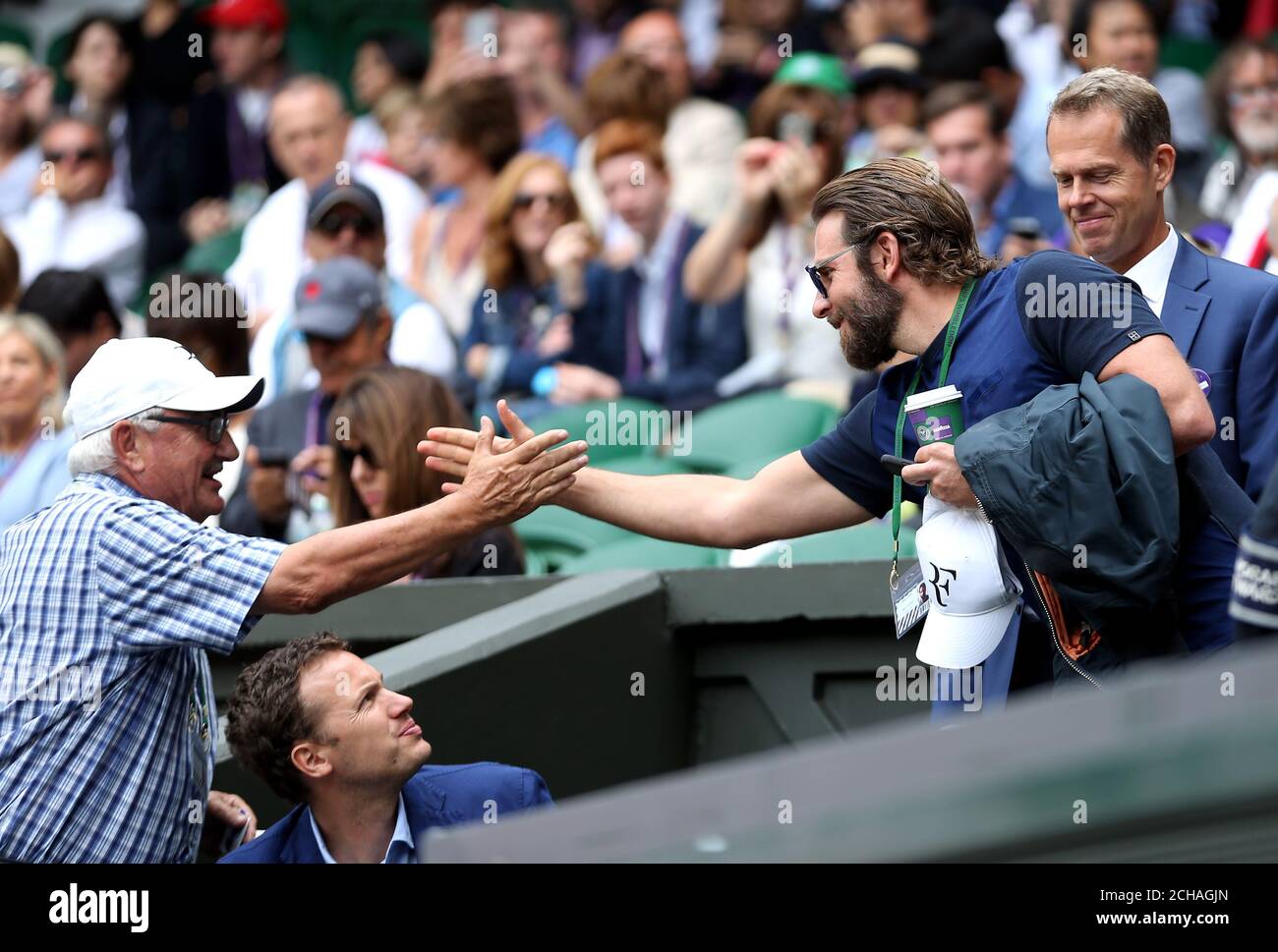 Robert Federer (left) greets Bradley Cooper in Roger Federer's players box on day eleven of the Wimbledon Championships at the All England Lawn Tennis and Croquet Club, Wimbledon. Stock Photo