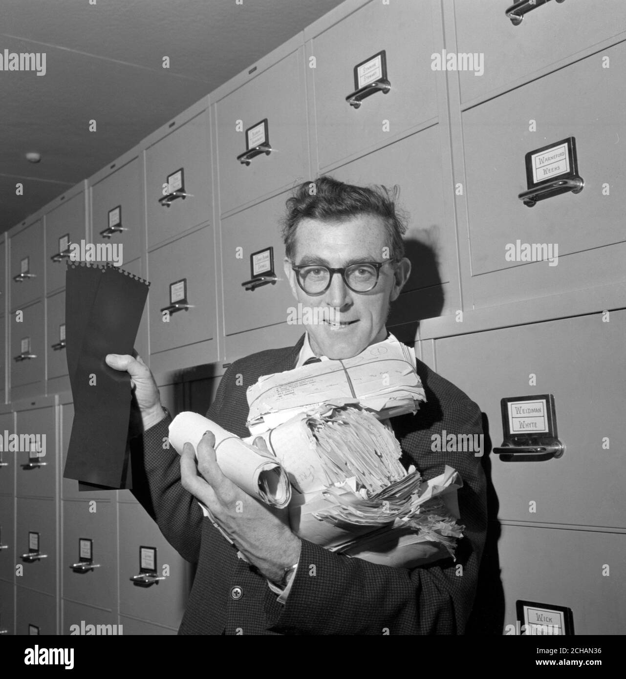 Bundles of Press Association 1964 General Election copy are held by a PA reporter, showing the contrast between the space taken up by information on paper and that stored on the NCR 315 Computer C.R.A.M. Cards. Though only 14-inches long, the cards contain on their MYLA-coated surfaces more information than the bundles of 'copy'. Stock Photo