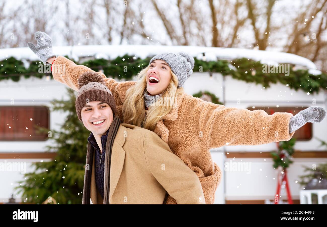 Happy winter couple having fun outdoors at campsite, guy piggybacking ...