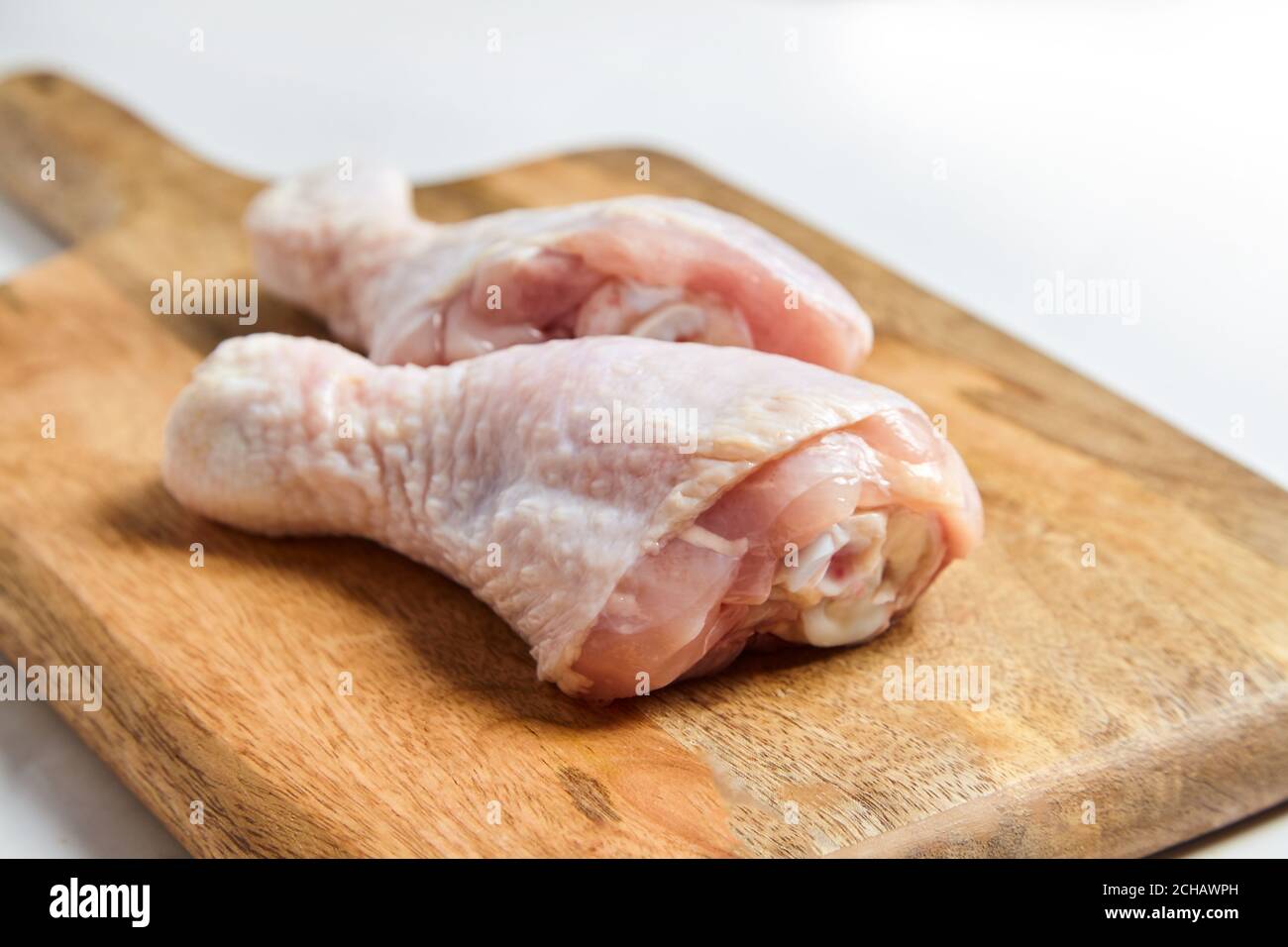 Chicken legs with skin lying on a wooden cutting board. Poultry meat