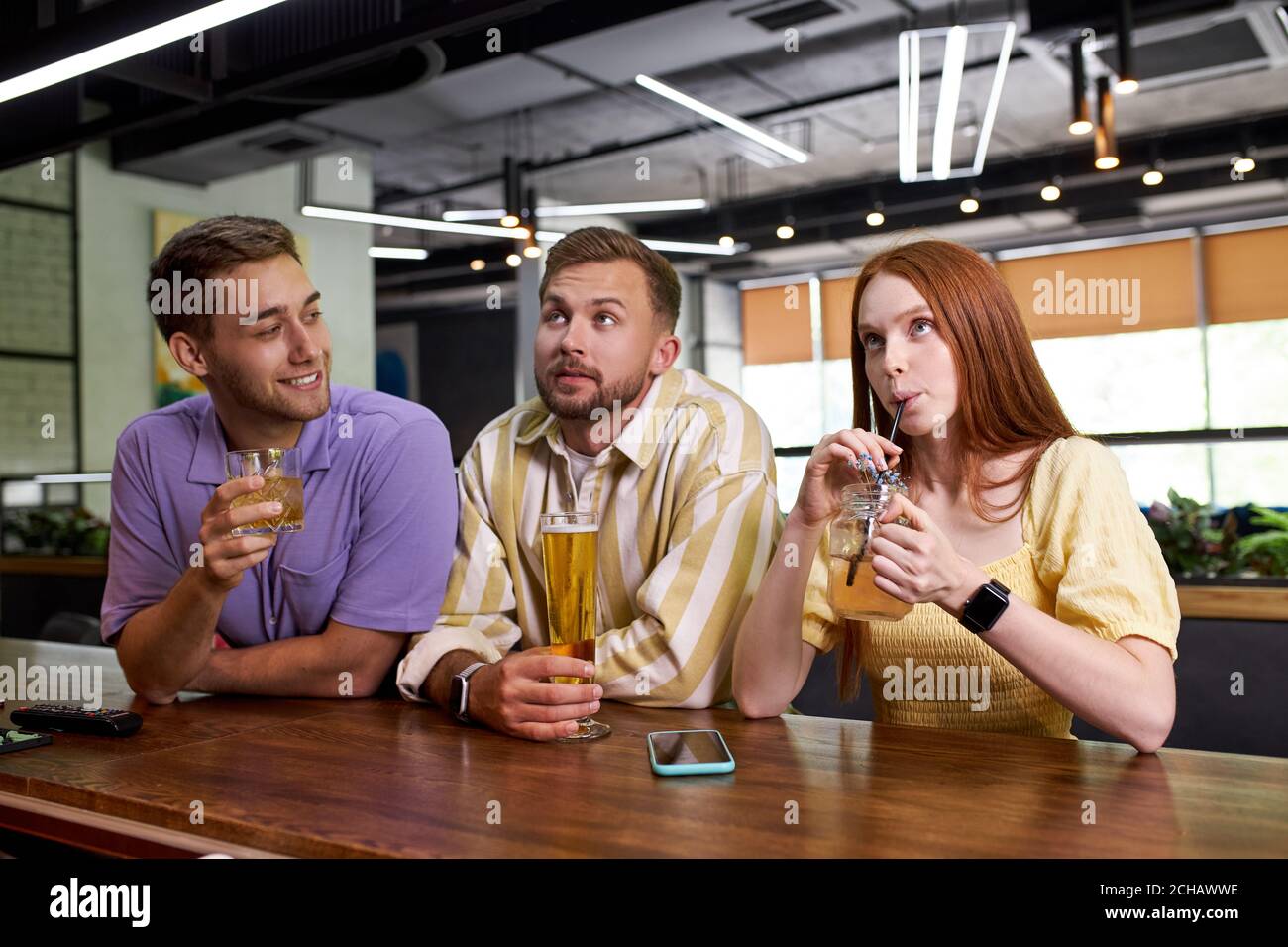 two male friends meet beautiful girl in bar, they have talk and some flirt. holidays, vacation, weekend concept Stock Photo