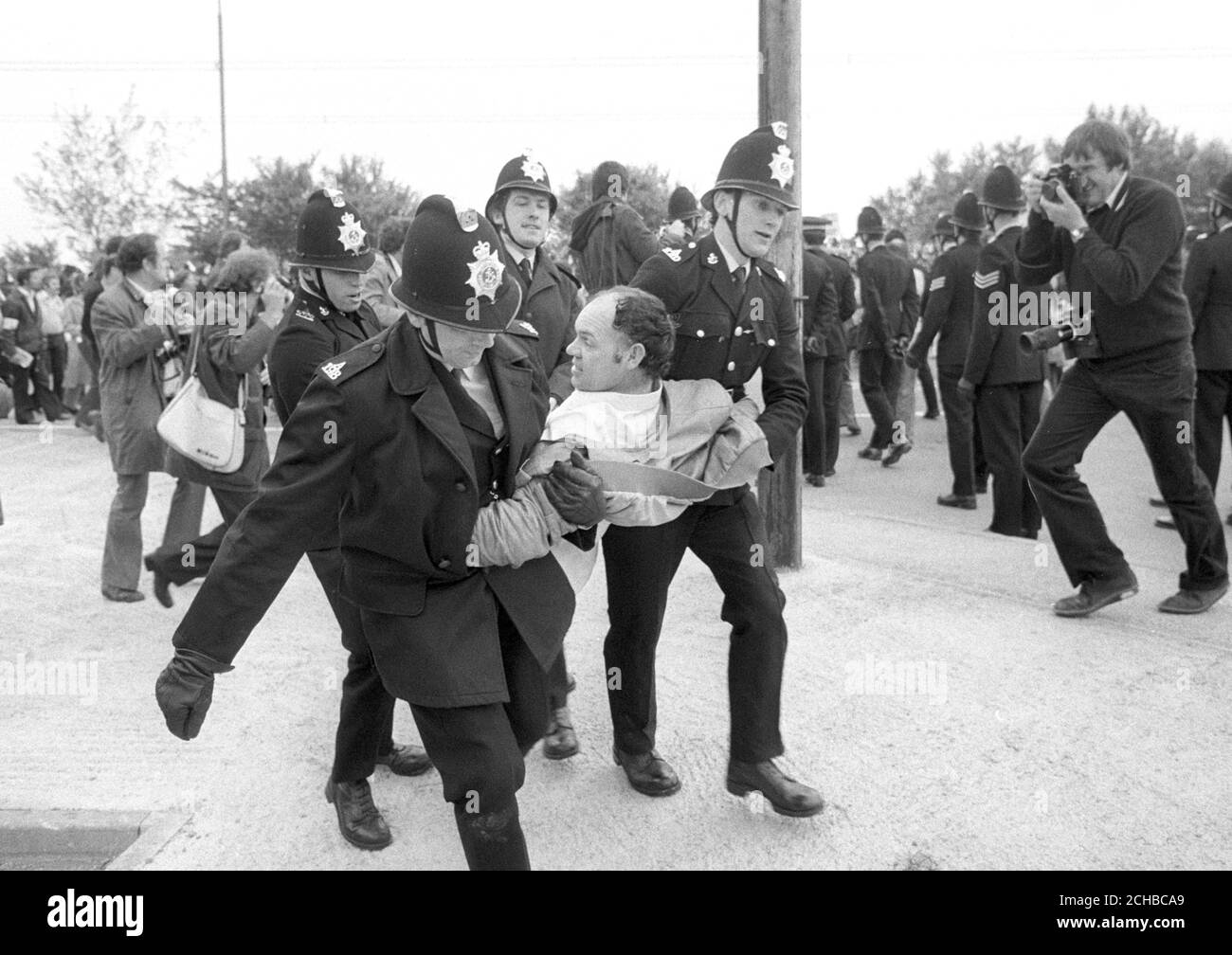 Four police officers carry off a man outside the Isle of Grain power station in Kent, where 31 people were arrested and two policeman injured during picket line clashes at the still-unfinished Â£570million complex. Stock Photo