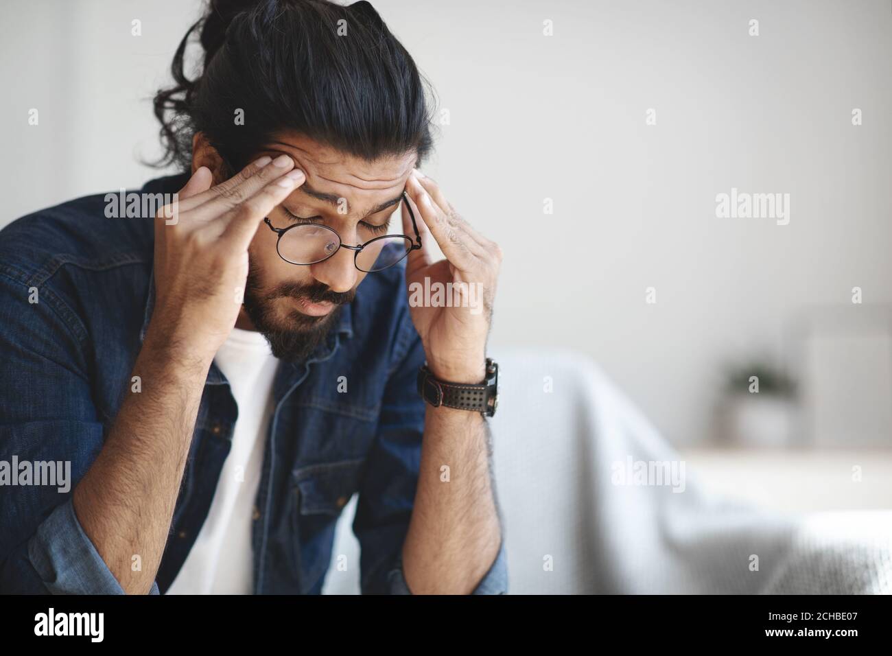 Young indian guy freelancer suffering from headache after hard working day Stock Photo